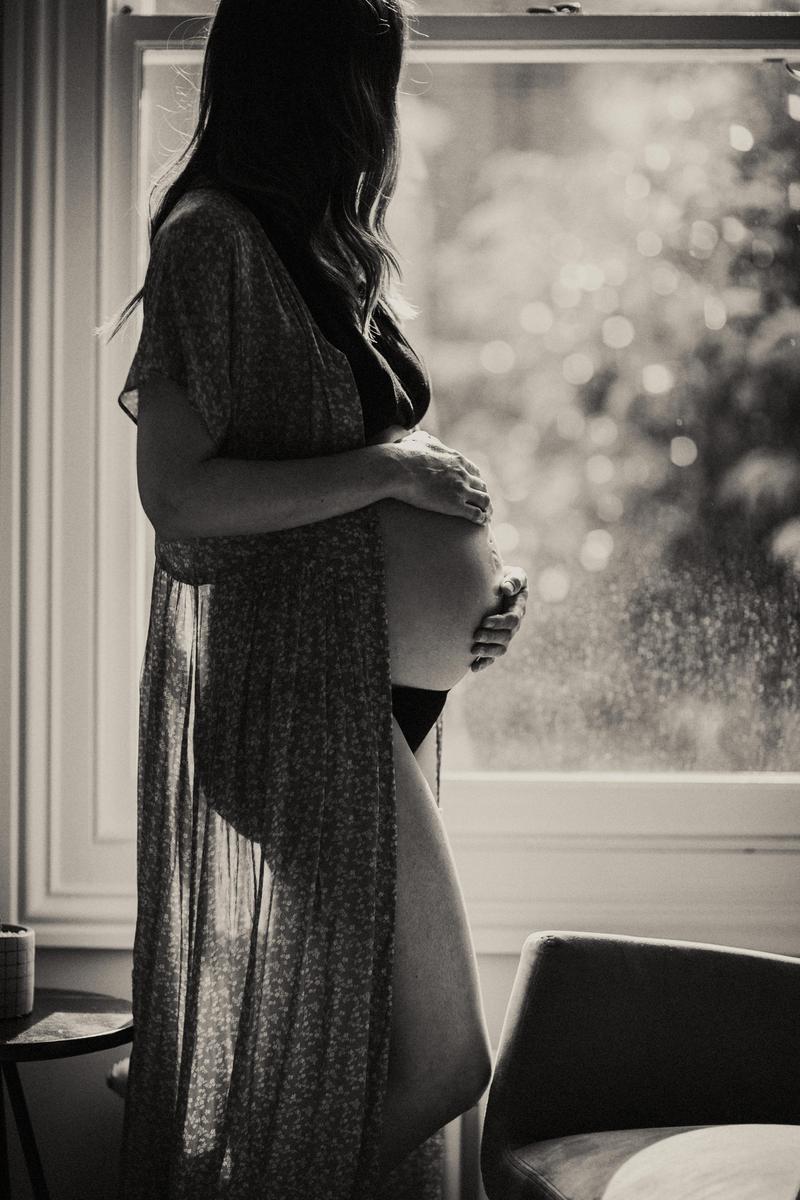 Photo noir et blanc dune femme enceinte posant ses mains sur son ventre