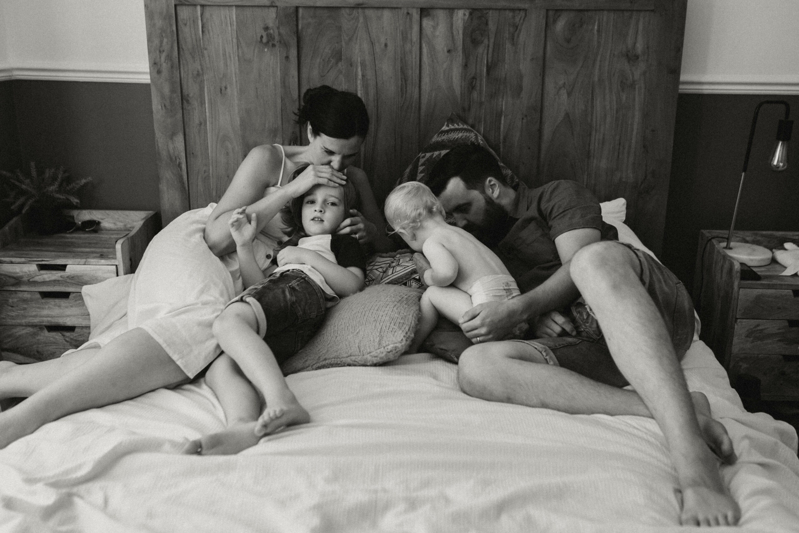 Parents embrassant leurs enfants sur leur lit pendant une séance photo famille à Nantes