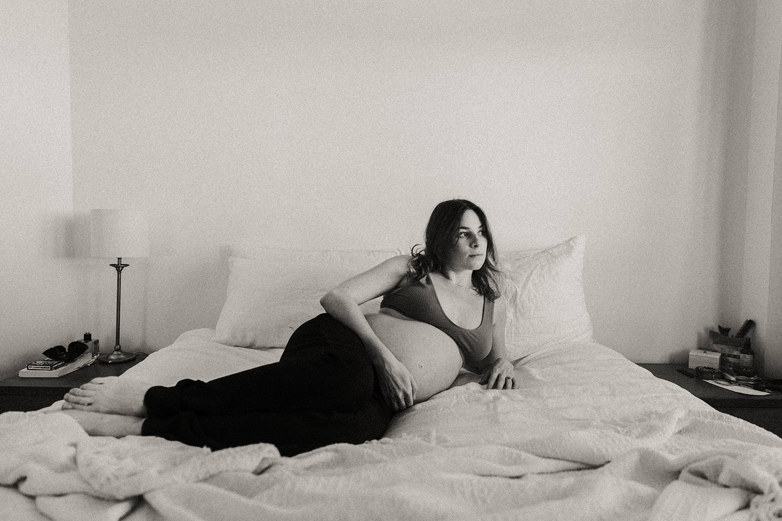 Femme enceinte allongée sur son lit lors d'une séance grossesse à Nantes