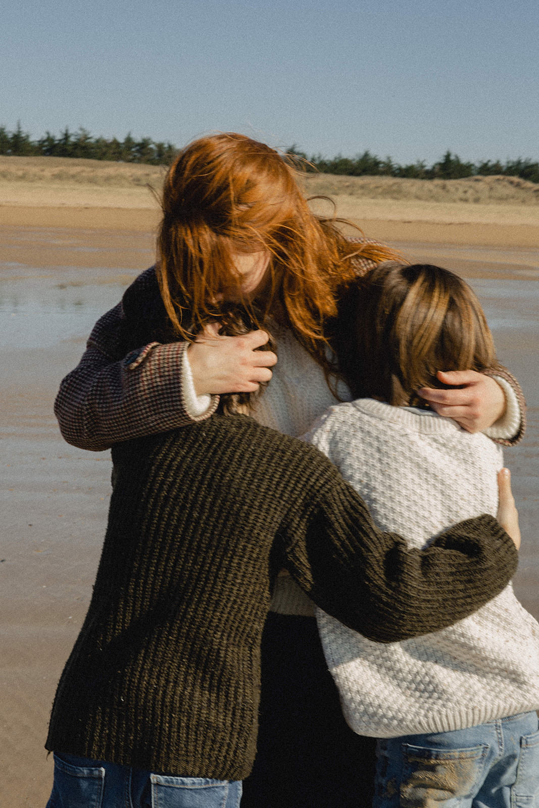 Maman embrassant ses enfants pendant une séance photo sur la plage en Vendée