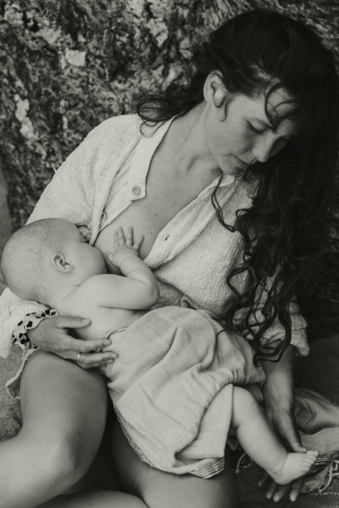 Gros plan en noir et blanc d'une maman allaitant sa fille pendant une séance photo famille à Belle Ile