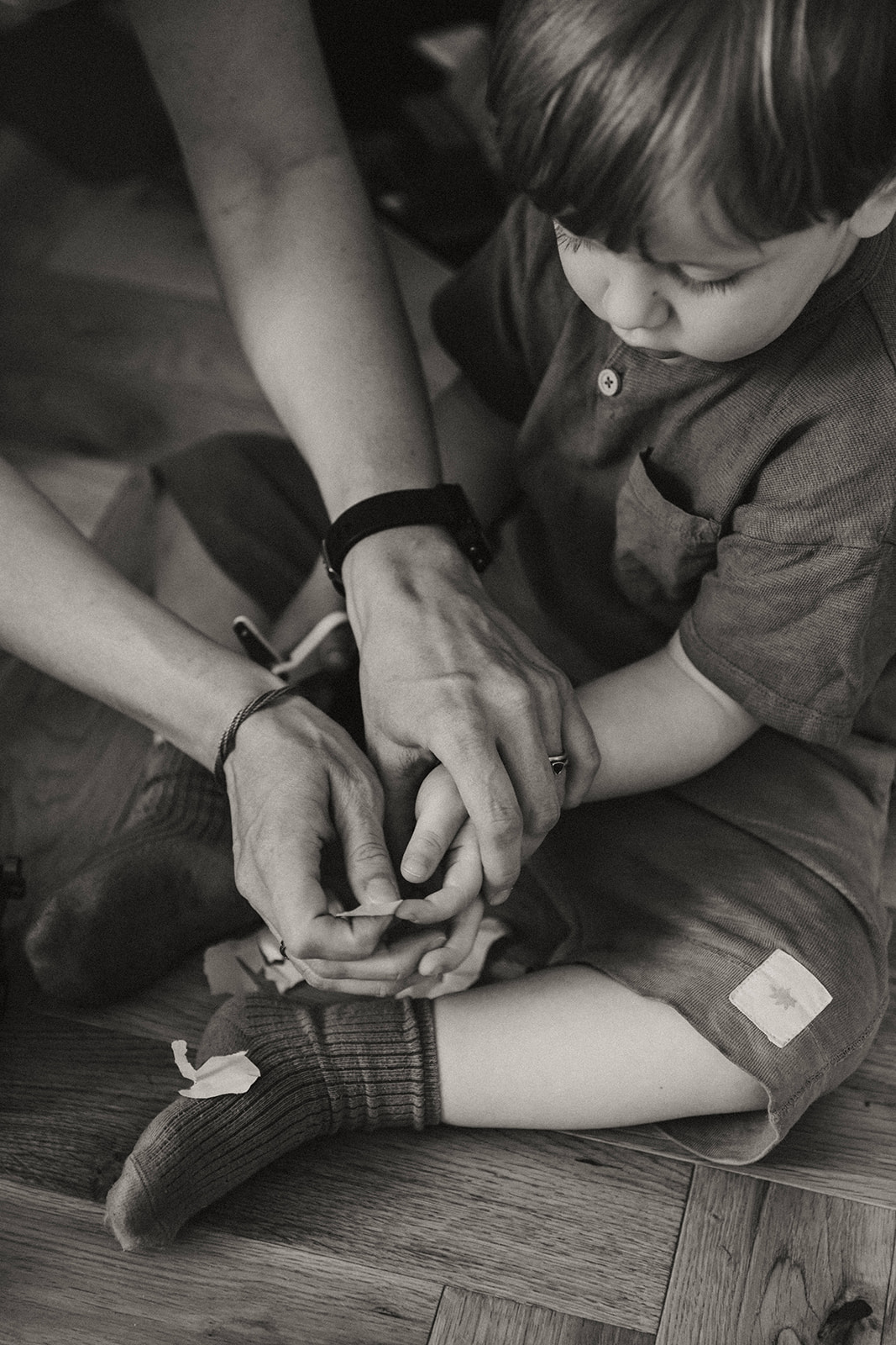 Gros plan sur les mains d'une maman aidant son enfant à découper avec des ciseaux, prise pendant une séance famille à Nantes