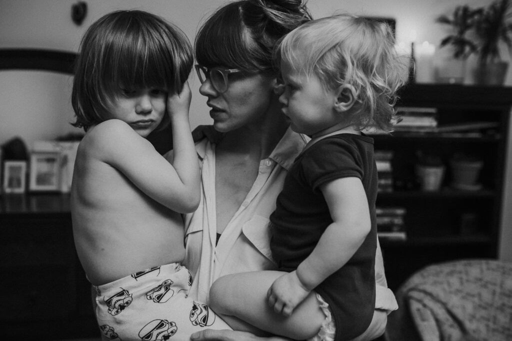 maman portant ses deux enfants dans ses bras lors d'une séance photo famille documentaire en noir et blanc à Reykjavik en Islande