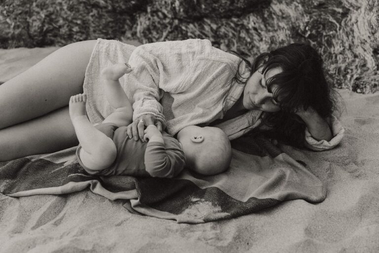 Maman et son bébé allongées sur la plage lors d'une séance photo motherhood